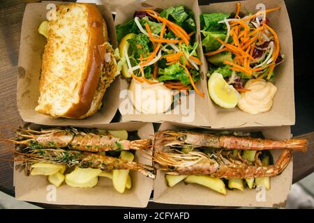 Fruits de mer dans des boîtes en papier sur la table. Cuisine de rue Banque D'Images