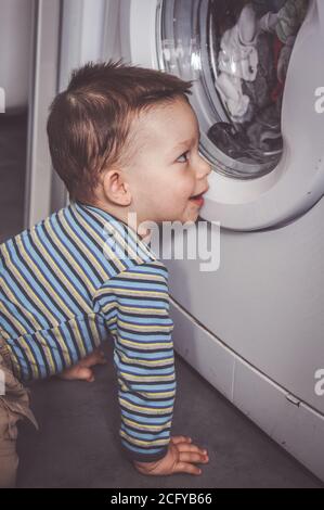 POZNAN, POLOGNE - 18 avril 2015 : petit garçon devant une machine à laver Banque D'Images