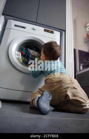 POZNAN, POLOGNE - 18 avril 2015 : petit garçon devant une machine à laver Banque D'Images