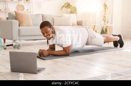 African Guy Training au portable faire de l'exercice de planche dans la chambre Banque D'Images