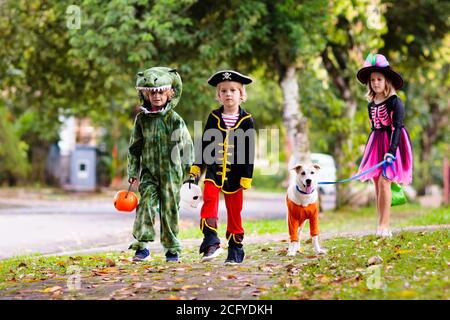 Les enfants se déguent en costume d'Halloween. Les enfants de couleur s'habillent avec un seau à bonbons dans la rue de banlieue. Petit garçon et fille trick ou traiter le wi Banque D'Images