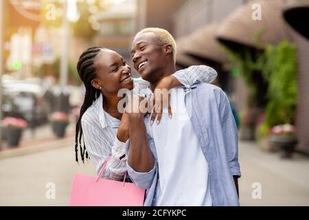 Bonne fille africaine américaine câlins homme avec des sacs de couleur près magasins Banque D'Images