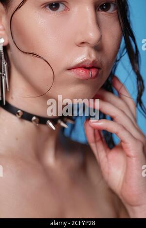 Portrait de belle femme gothique avec piercings et autres accessoires en studio sur fond bue. Émotif, jeune visage. Émotions humaines, exp. Facial Banque D'Images
