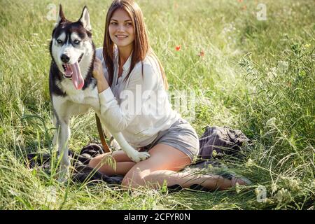 Belle jeune femme jouant avec un chien Husky drôle à l'extérieur du parc. L'été et le coucher du soleil. Amour inconditionnel. Animal de compagnie Husky préféré de Sibérie. Déshumidificateur animal Banque D'Images