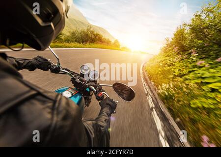 Vue du conducteur de moto sur la conduite en paysage alpin pendant lever du soleil Banque D'Images