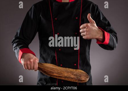 Gros plan du chef principal tenant une planche à découper en bois. Concept de préparation des aliments, prêt pour le placement des produits. Banque D'Images