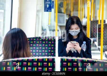 7 septembre, Londres, Royaume-Uni - Femme asiatique assise sur le tube dans une voiture de la Metropolitan Line vide portant un masque facial pendant la pandémie du coronavirus Banque D'Images