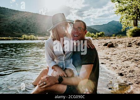 Portrait d'un jeune couple qui s'embrasse et rit sur le bord du lac Banque D'Images