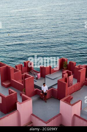 Jeune homme latin méditatif à 'Muralla Roja' de Calpe, Espagne Banque D'Images