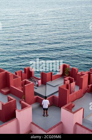 Jeune homme latin méditatif à 'Muralla Roja' de Calpe, Espagne Banque D'Images