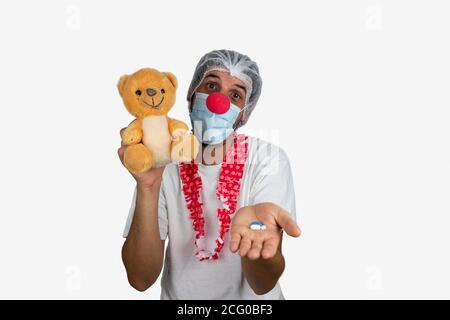 Infirmière ou médecin, vêtu de vêtements de protection et de nez clown pour divertir les enfants pendant le traitement à l'hôpital. Donner des pilules pour enfants. Covid-19, CO Banque D'Images