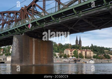 Vue depuis le pont en acier historique de la rivière Vltava à Prague en direction du château de Vysehrad et du remblai au bord de la rivière. Banque D'Images