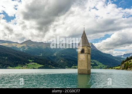 Le sommet de l'ancien clocher de Curon (Graun) émerge des eaux du lac Resia, contre un ciel spectaculaire, au Tyrol du Sud, en Italie Banque D'Images