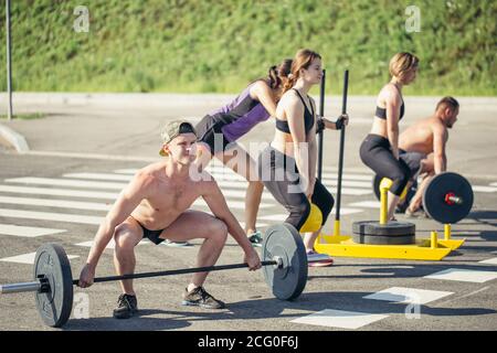 groupe d'athlètes faisant des exercices avec des cloches, poussant des traîneaux, balançoire de kettlebell Banque D'Images