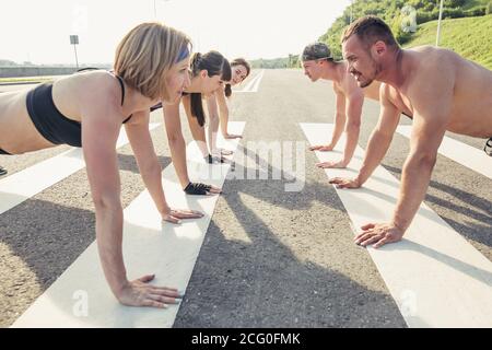 Groupe d'adultes effectuant des exercices physiques à l'extérieur salle d'entraînement physique polyvalente avec lumière vive elles Banque D'Images