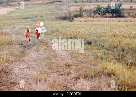 Enfant mignon avec des ballons. Petite fille et garçon sur une promenade. Profitez de l'instant. Enfant heureux en été dans la nature. Garde d'enfants. L'enfant a la joie d'été. Banque D'Images