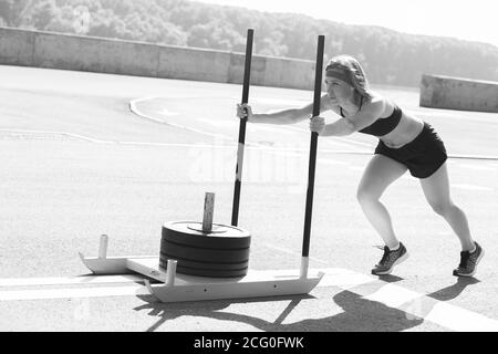 femme poussant l'équipement d'exercice de prowler. Faites de la musculation à la salle de sport Cross Fit Gym Banque D'Images