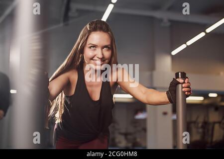 Une jeune femme musclée et forte pousse l'équipement d'exercice du prowler sur gazon artificiel. Faites de la musculation à la salle de sport Cross Fit Gym. Banque D'Images