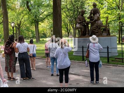 Les gens se regroupent autour du monument des pionniers des droits des femmes sur la promenade littéraire dans Central Park à New York le jour de son dévoilement, le mercredi 26 août 2020. La statue, de gauche à droite, de Sojourner Truth, Susan B. Anthony et Elizabeth Cady Stanton commémore le 100 e anniversaire du 19e amendement qui donne aux femmes le droit de vote. Le sculpteur est Meredith Bergmann et est le seul monument de Central Park représentant de vraies femmes. (© Richard B. Levine) Banque D'Images