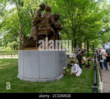 L'artiste Meredith Bergmann arrange des fleurs devant son monument des pionniers des droits des femmes alors que les travailleurs du département des Parcs terminent l'installation, sur la promenade littéraire dans Central Park à New York le jour de son dévoilement, le mercredi 26 août 2020. La statue, de gauche à droite, de Sojourner Truth, Susan B. Anthony et Elizabeth Cady Stanton commémore le 100 e anniversaire du 19e amendement qui donne aux femmes le droit de vote. Le sculpteur est Meredith Bergmann et est le seul monument de Central Park représentant de vraies femmes. (© Richard B. Levine) Banque D'Images