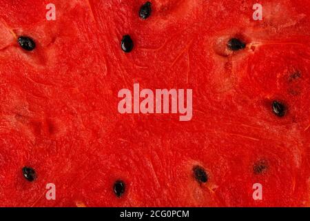 La pulpe d'un melon d'eau juteux rouge avec des graines comme un arrière-plan Banque D'Images