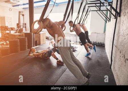 Tree séduisant jeune homme et femme adultes faisant tirer sur la barre de l'onduleur en contre insérer la formation de sport avec des murs en briques et des tapis noir Banque D'Images