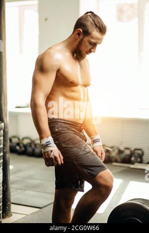 jeune homme se préparant pour l'entraînement de barbell dans la salle de gym. Haltérophilie, haltérophilie, équipement d'ajustement croisé. Sports, fitness - concept de mode de vie sain. Banque D'Images