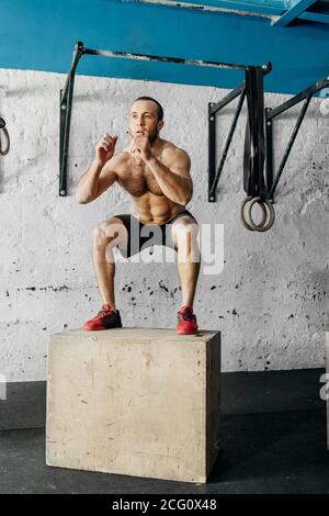 Mettre en forme les jeunes qui font des sauts de boîte dans une salle de gym Banque D'Images