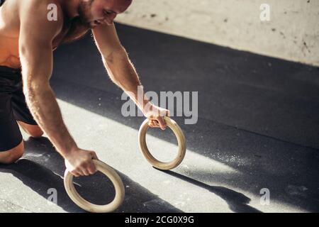 Le jeune homme de stron fait des push-up par des anneaux. Banque D'Images