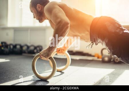 Le jeune homme de stron fait des push-up par des anneaux. Banque D'Images