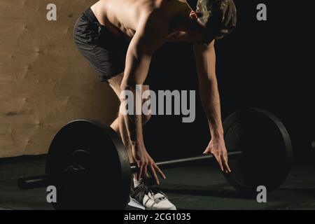 Un jeune homme qui se prépare à l'entraînement avec des haltères à la salle de gym. Ajustement croisé. Banque D'Images