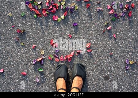 Les pieds du danseur de ballet sur un sol en asphalte avec quelques pétales entourent. Pieds se posant ensemble. Vue horizontale. Banque D'Images