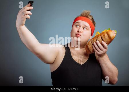 L'homme drôle de graisse avec sandwich en main fait selfies Banque D'Images