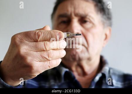 Homme âgé mesurant la température corporelle avec thermomètre au mercure. Concept de fièvre, traitement froid, symptômes du coronavirus Banque D'Images