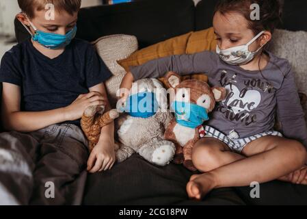 Jeune fille et jeune garçon avec des masques jouant avec des animaux sur la table Banque D'Images