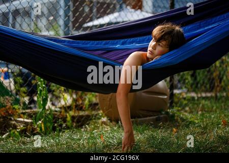 Portrait d'un beau garçon reposant dans un hamac en regardant dans distance Banque D'Images