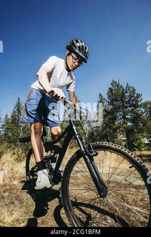 Un jeune garçon fait son vélo tout terrain sur un sentier dans le nord de l'Idaho. Banque D'Images
