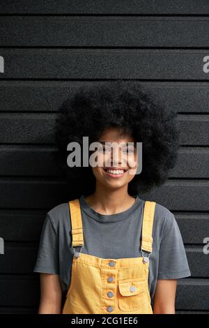 Bonne femme africaine hippster avec cheveux afro regardant l'appareil photo, portrait vertical. Banque D'Images