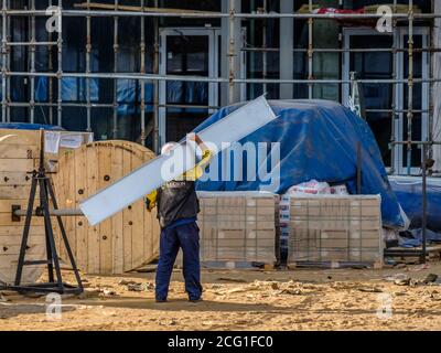 Moscou. Russie. 06 septembre 2020 les travailleurs de la construction qui travaillent dans les uniformes et les casques de sécurité sur le chantier transfèrent manuellement la construction Banque D'Images
