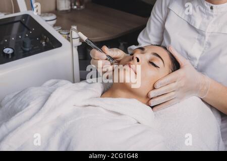 Procédures de levage de la peau du visage sur une dame brune couché un salon de spa guéri avec un nouvel appareil Banque D'Images