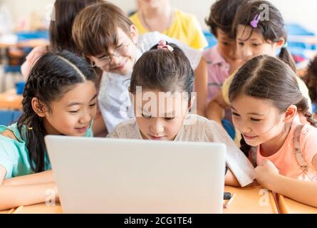 Des enfants heureux regardant l'ordinateur portable dans la salle de classe