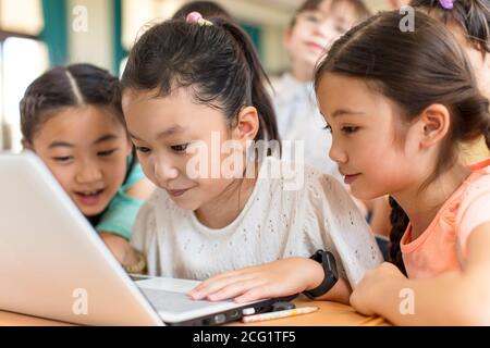 Des enfants heureux utilisant l'ordinateur portable dans la salle de classe Banque D'Images