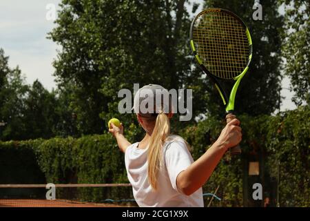 Une jeune femme en t-shirt blanc sert la balle de tennis Banque D'Images