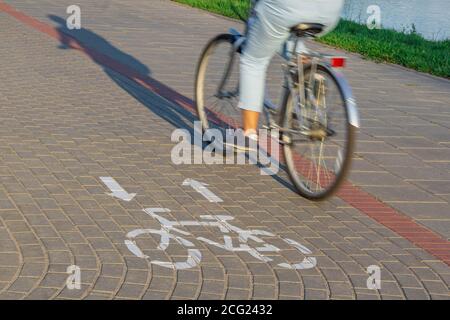 Cycliste en mouvement flou conduite le long de la voie de vélo avec l'ombre du cycliste et du panneau de vélo. Concept de transport écologique Banque D'Images