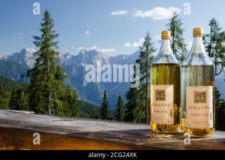 Août 2020. Dolomites, Italie. Deux bouteilles de grappa aromatique distillées dans un refuge dans les Dolomites. En arrière-plan les montagnes par une journée ensoleillée Banque D'Images