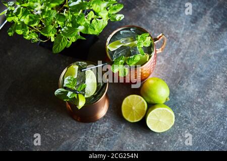 Cuba libre, rhum et Cola buvez avec du citron vert dans des mugs en cuivre sur un bar Banque D'Images