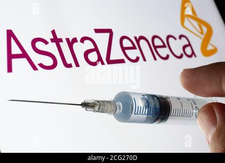 Concept de vaccin AstraZeneca Oxford. Seringue sur écran blanc et logo AstraZeneca sur fond flou. Banque D'Images