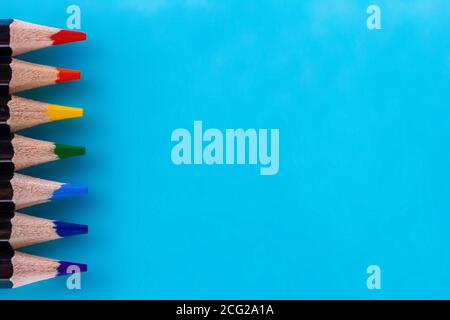 Bannière créative minimale. Ensemble de crayons de couleur bois noir disposés en ligne sur fond bleu. Copier l'espace. Arrière-plan de la papeterie Banque D'Images