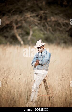 homme africain dans le bush africain portant un chapeau et lunettes de soleil au soleil éclatant Banque D'Images