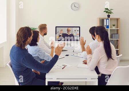 Les employés de l'entreprise qui travaillent au bureau ont une réunion en ligne avec leur PDG utilisant un ordinateur de bureau Banque D'Images